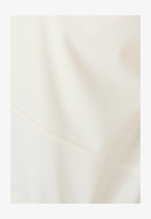 Tissu blanc présentant une texture lisse et une légère brillance, avec un détail de couture horizontale et un léger effet de drapé.