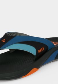 Ανδρικά μαύρα και μπλε σανδάλια Reef με πορτοκαλί λογότυπο, μαλακό πάτο και υφή στη σόλα, σχεδιασμένα για καθημερινή χρήση.