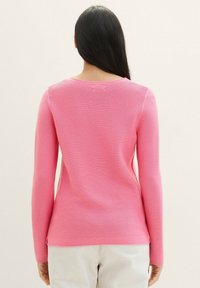 Rosa gerippter Longsleeve-Pullover mit rundem Halsausschnitt und strukturierter Oberfläche, mit taillierter Silhouette und dezenten Seitenschlitzen.