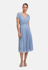 Robe bleu clair, à mi-longueur, avec un col en V, des manches courtes et une taille froncée. Le tissu a un léger éclat avec une jupe fluide.