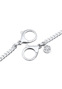 Silverfärgad kedjebracelet med en snabblås och en liten cirkulär berlock med ett geometriskt mönster som reflekterar en glänsande metallisk yta.