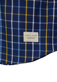Modré a žluté kostkované bavlněné plátno s bílými akcenty, na spodní straně s cedulkou "POLO CLUB" a sloganem.