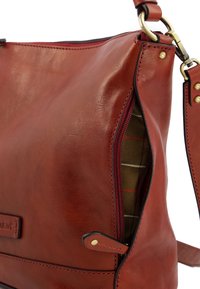 Sac à épaule en cuir rouge avec fermeture éclair, présentant une surface texturée et un doublure en tissu à carreaux. Accents en métal doré.