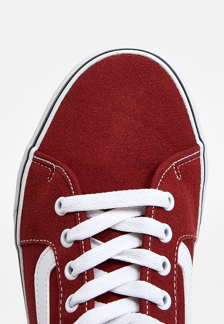Zapatilla de ante rojo con cordones blancos, presenta una parte superior texturizada, puntera redonda y suela de goma blanca. El panel lateral tiene un acento de logo blanco.