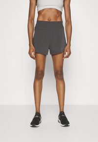 Bermudas deportivas grises con una textura suave y una cintura elástica, combinadas con zapatillas negras. Diseño minimalista, adecuado para deportes o ejercicio.