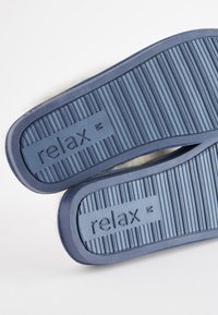 Sinised kummist sandaalid tekstuurse soonilise tallaga. Rihmal on üles punnitatud sõna "relax". Disainis on sile serv ja ümardatud kuju.