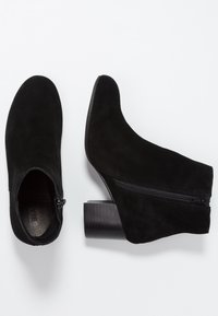 Stivaletti alla caviglia in suede nero con punta arrotondata, cerniera laterale e tacco largo e robusto. Texture liscia e design semplice per versatilità.