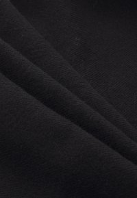 Black fabric with a soft, textured surface featuring a diagonal weave pattern and folded layers, displaying variations in light and shadow.