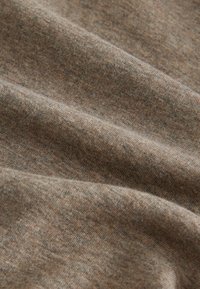 Brunt stof med en blød, struktureret overflade, der har et let meleret udseende og bløde folder, hvilket indikerer et letvægtsmateriale.