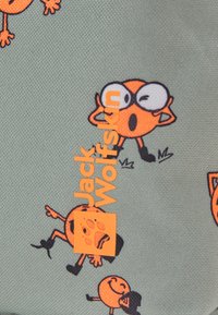 Visages de dessins animés oranges avec diverses expressions et des bottes noires sur un tissu gris texturé, avec le nom de marque "Jack Wolfskin" et le logo d'empreinte de patte en orange.