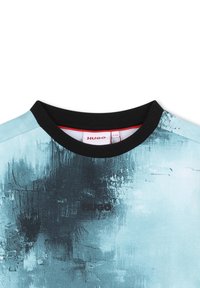 T-shirt à manches courtes avec un motif bleu et un col rond noir, présenté avec un design abstrait texturé et un logo "HUGO" noir sur le devant.