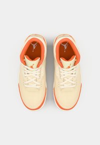 Zapatillas beige con acentos naranjas, con un upper texturizado, cordones blancos, cuello acolchado y un logo de Jumpman en la lengüeta y la plantilla.