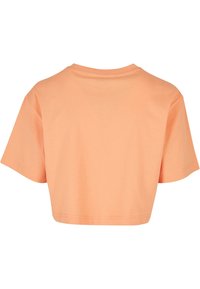 T-shirt court à manches courtes couleur pêche avec un col rond, montré de dos sur fond blanc.