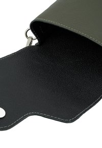 Borsetta in pelle verde con un interno nero texturizzato. Presenta una cerniera argentata e dettagli di cucitura lungo i bordi.