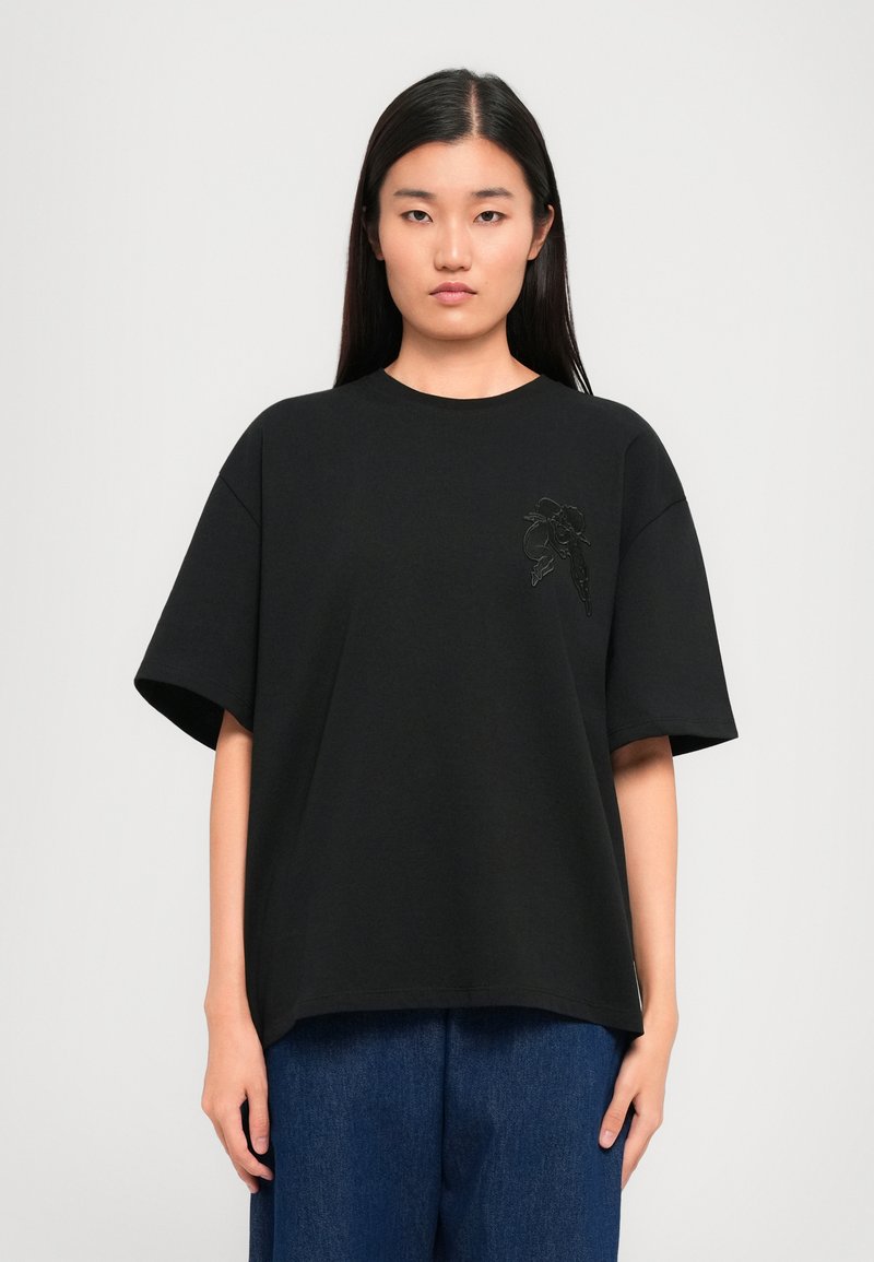 Μαύρη κοντομάνικη μπλούζα T-shirt με στρογγυλή λαιμόκοψη και κεντητό σχέδιο στην αριστερή πλευρά. Λαμπερός ύφασμα με χαλαρή εφαρμογή.