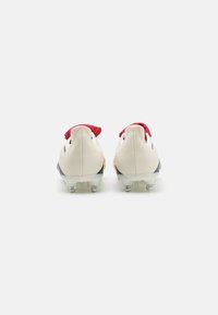 White and red soccer cleats with a textured leather upper, featuring a streamlined design, transparent outsole, and metallic studs.