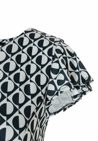 Kurzärmliges Kleid in einem schwarz-weißen geometrischen Muster mit Rüschensäumen, gefertigt aus einem glatten, leichten Stoff.