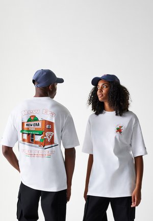 Le t-shirt bianchi presentano stampe grafiche: una pizzeria sulla schiena e un piccolo logo sul davanti, indossati con cappellini blu navy. I pantaloni cargo neri sono visibili.
