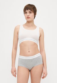 Hvit bomullsbralette med rund utringning og grå bomullshipstershorts med en hvit merket midje. Jevn tekstur, tettsittende design.