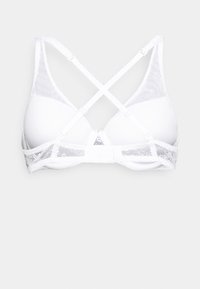 Soutien-gorge blanc avec une finition lisse, des accents en dentelle et des bretelles croisées dans le dos. Comprend une fermeture à crochets et un œil et des bonnets en douceur.