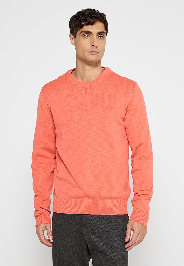 Korallfarbener Pullover aus weichem, strukturiertem Stoff; Rundhalsausschnitt, gerippte Bündchen und Saum; mit dezentem Branding auf der Brust.