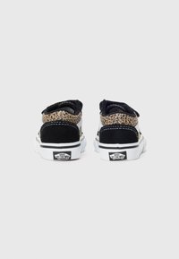Ein Paar niedrig geschnittene Vans-Sneaker mit Leopardenmuster und schwarzen Wildlederdetails, von hinten betrachtet auf einem schlichten weißen Hintergrund.