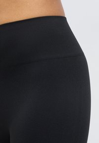 Schwarze Leggings mit hoher Taille aus Rippenstoff, mit einem strukturierten Muster und einem glatten Bund mit dezentem Glanz.