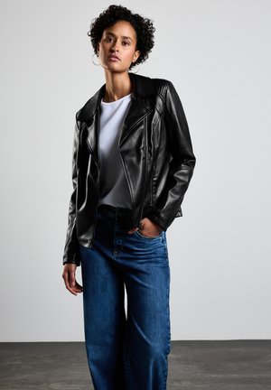 Black leather motorcycle jacket with a notched collar, zip closure, detailed stitching, and fitted design. Paired with blue wide-leg jeans.