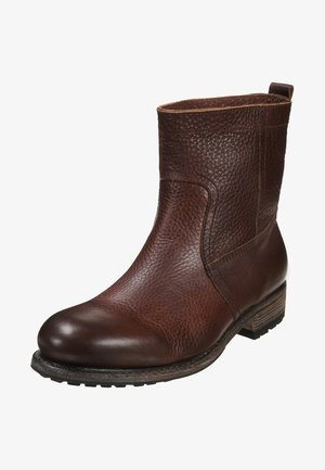 Bottine en cuir marron avec finition texturée, bout rond, talon empilé et design discret. Présente des coutures subtiles et une languette de maintien.