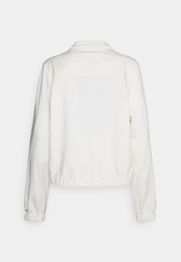 Veste blanche à manches longues avec col, poignets et taille élastiques, en tissu doux, et un design simple sans logos ou motifs visibles.