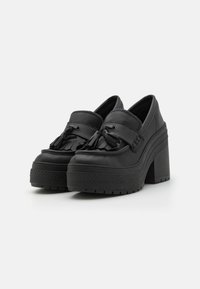 Sorte plattform loafers med en kraftig hæl, med en teksturert gummisåle og frynsedetaljer foran. Glatt skinnmateriale.