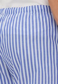 Blå og hvite stripete bukser med elastisk midjebånd, laget av et lett stoff og med vertikal stripemønster.