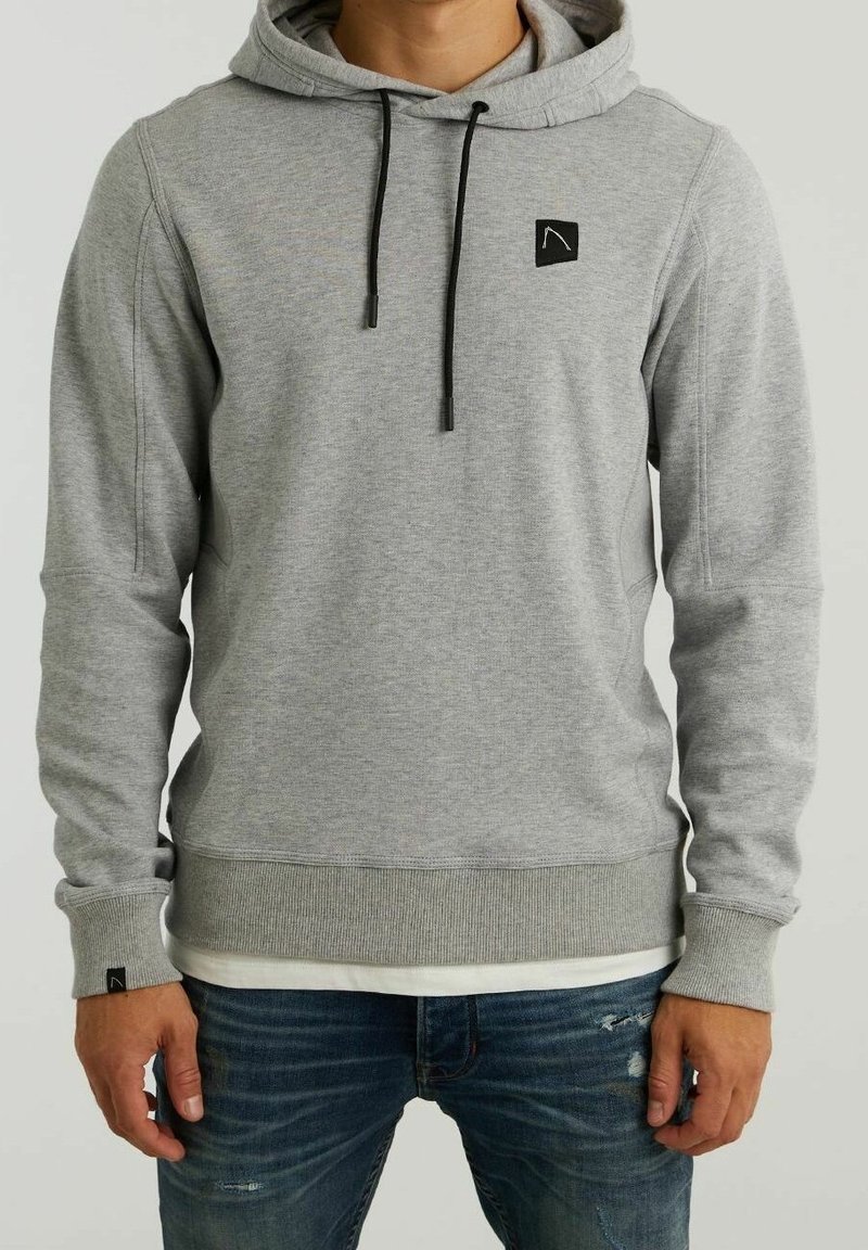 Sudadera gris hecha de un tejido suave, con un bolsillo frontal, cordones en la capucha y un pequeño parche con el logo en el pecho. Puños y dobladillo acanalados.