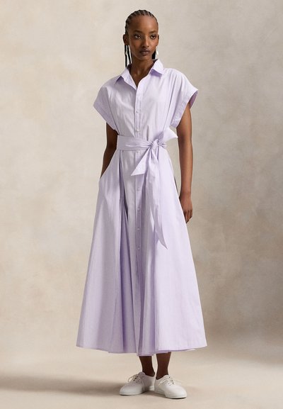 Φόρεμα σε ανοιχτό μωβ λεβάντας με κοντά μανίκια, κουμπώνει μπροστά, ζώνη στη μέση και πλαϊνές τσέπες. Διαθέτει κάθετες ρίγες και φαρδιά φούστα.