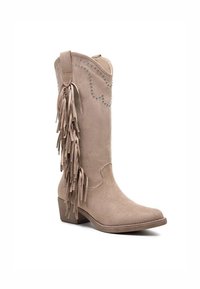 Botte de cow-boy en daim beige mi-mollet avec des franges sur le côté, des clous argentés décorant le haut, et un petit talon en bois.