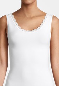 Top bianco a coste con scollatura in pizzo scallop femminile. Il tessuto è morbido e ha una silhouette aderente per garantire comfort.