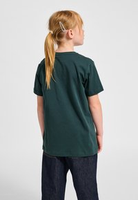 Grøn t-shirt med korte ærmer i bomuld, med rund hals og løs pasform, kombineret med mørkeblå denimjeans.