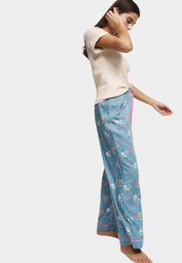 Lätt, ribbad beige topp kombinerad med blå blommiga pyjamasbyxor med rosa detaljer, vida ben och en mjuk textur.