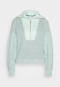 Hellgrüner Strickpullover in Minzfarbe mit einem Viertelreißverschluss am Kragen, der ein strukturiertes Design und ein kontrastierendes, einfarbiges Paneel auf der oberen Vorderseite aufweist.