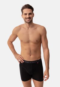 Boxer da uomo neri realizzati in tessuto morbido con una vita grigia etichettata "Danish Endurance". Presentano un design aderente senza pattern visibili.