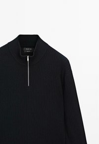 Zwarte gebreide trui met hoge kraag, kwart-rits aan de voorkant en geribbelde textuur. Etiket leest "Massimo Dutti."