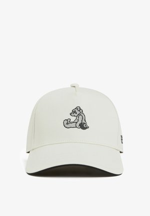 Gorra blanca con visera curvada, que presenta un gráfico de oso bordado en negro en la parte frontal y un pequeño logo en el lado. Tela texturizada.