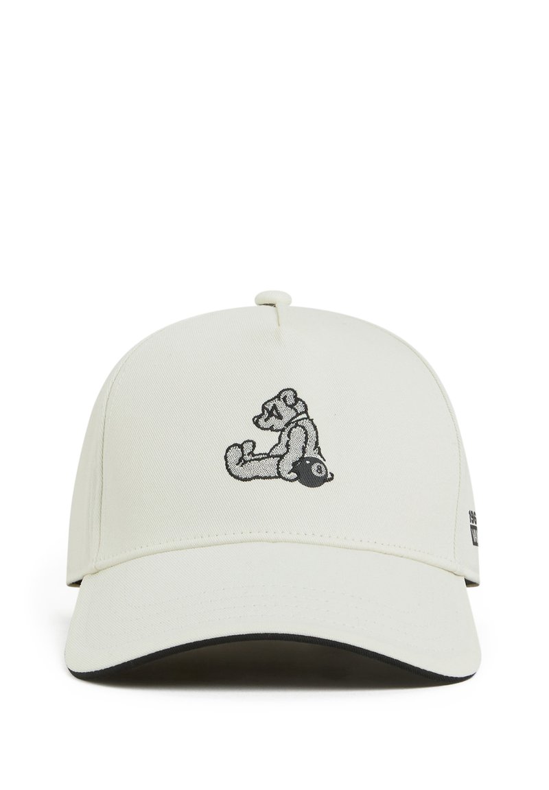 Gorra blanca con visera curvada, que presenta un gráfico de oso bordado en negro en la parte frontal y un pequeño logo en el lado. Tela texturizada.