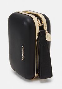 Czarna skórzana etui z złotym zamkiem i okuciami, z teksturowanym paskiem i wytłoczonym logo marki. Kompaktowy i prostokątny kształt.