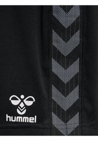 Sort sportsstof med en hvid Hummel-logo og et struktureret chevronmønster i grå langs siden. Glat tekstur med kontrasterende detaljer.