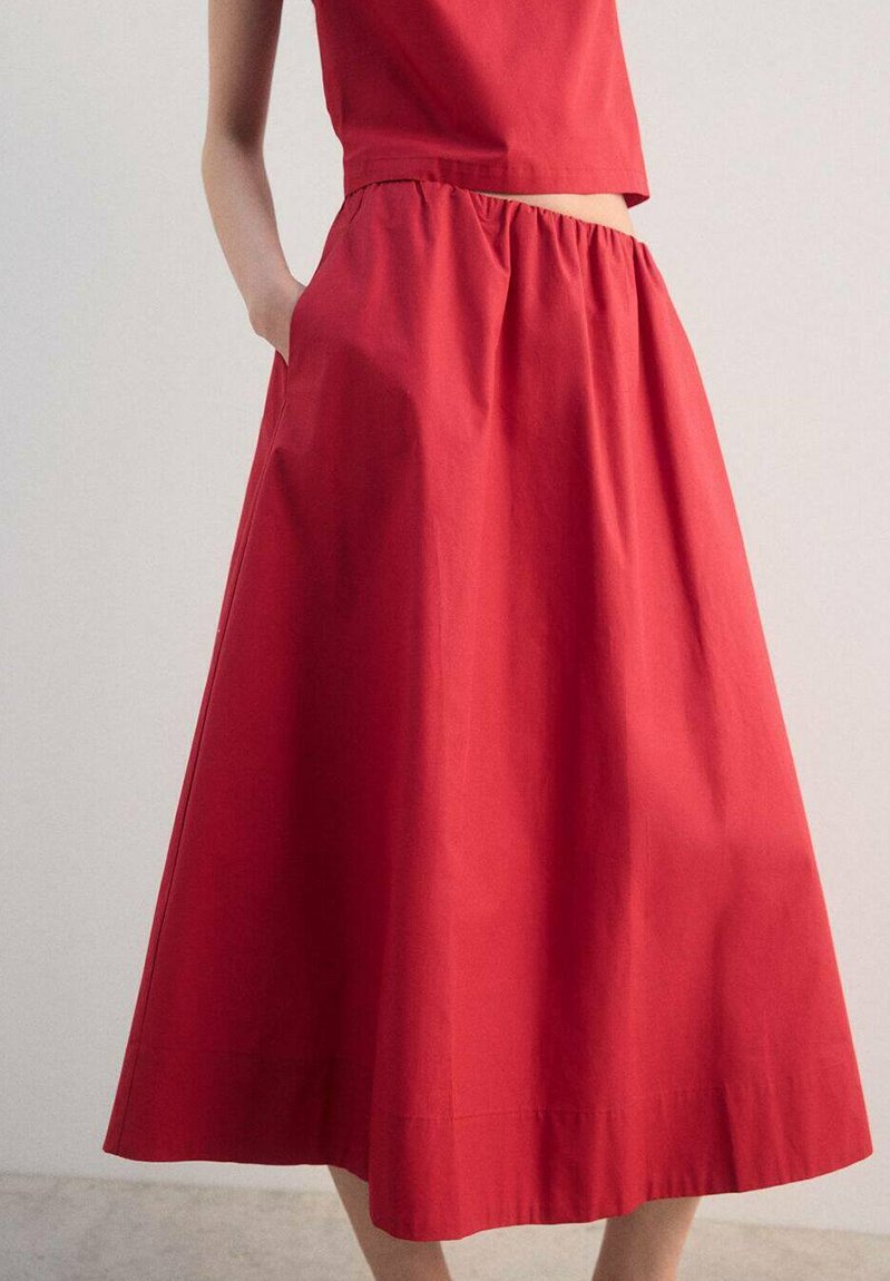 Červená sukně ke kolenům z hladké látky s řaseným pasem a bočními kapsami, s čistým, nenápadným designem.