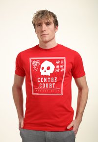 Červené bavlněné tričko s bílou grafikou lebky a textem "CENTRE COURT RACKET CLUB" v čtvercovém designu. Krátké rukávy, kulatý výstřih.