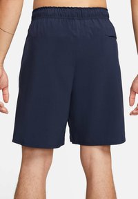 Navy-blue athletic shorts with an elastic waistband, side pockets, and a above-the-knee length. Smooth fabric with a lightweight design.