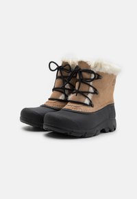 Brune suede støvler med en hvit pelskrage og svarte gummisåler. Med svarte snøringer og teksturerte flater for grep og varme.