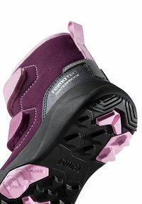 Zbliżenie na fioletową i różową, wodoodporną podeszwę buta turystycznego z głębokim bieżnikiem i widocznym napisem marki "rematec WATERPROOF".